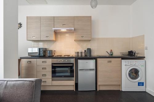 a kitchen with a stove and a dishwasher at Trafford Stays in Manchester