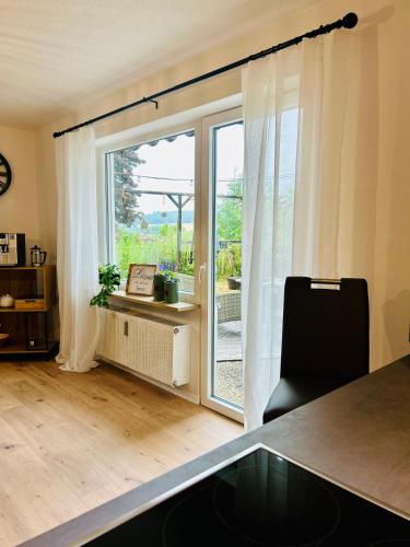 a kitchen with a sliding glass door with a table and a chair at Das Auental-Appartment in Köditz