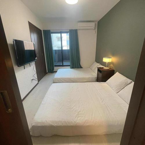 a hotel room with two beds and a flat screen tv at OSAKA FUJI STAY namba in Osaka