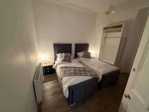 two beds in a small bedroom with two lamps at Musselburgh Links B&B in Musselburgh