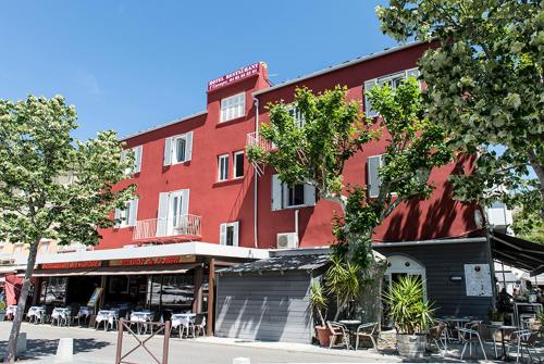 a red building with tables and chairs in front of it at Hotel Restaurant L'Europe in Saint-Florent