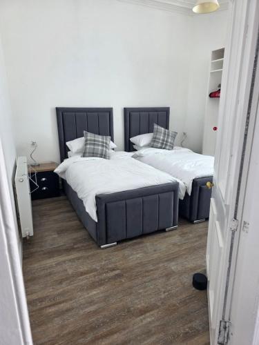 two beds in a bedroom with wood floors and white walls at Musselburgh Links B&B in Musselburgh