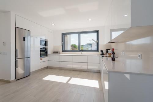 a white kitchen with white cabinets and a window at Dino Villa with ocean view in Casal do Cigano