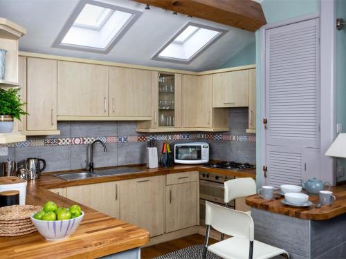 a kitchen with wooden cabinets and a table with a bowl of fruit at 2 Bed in Brecon Town BN140 in Brecon