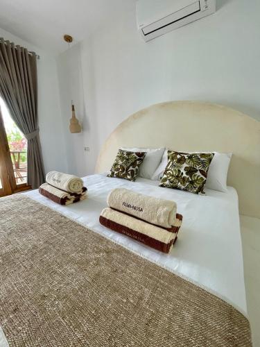 a large white bed with two towels on it at Alma Nusa Penida in Nusa Penida
