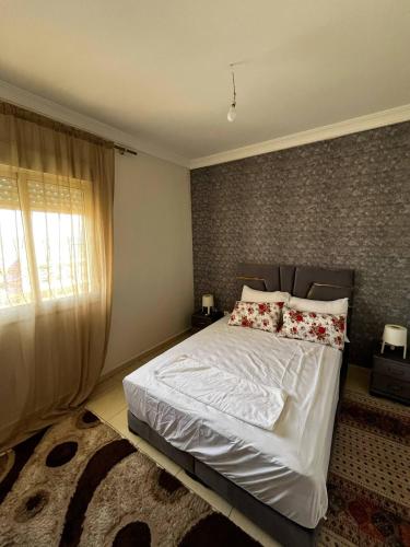 a bedroom with a white bed with pillows and a window at appartement Marrakech in Oulad Akkou