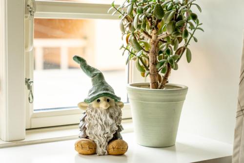 a gnome sitting on a window sill next to a plant at Akaciegaarden Bed & Breakfast in Hårlev