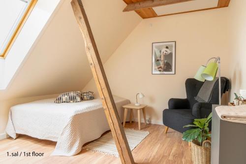 a bedroom with a bed and a chair at Akaciegaarden Bed & Breakfast in Hårlev