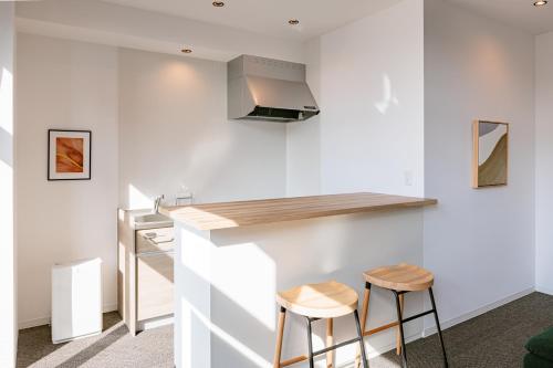 a kitchen with white walls and a counter and stools at LUX by Hotel BAL in Fukuoka