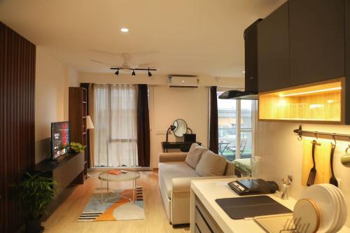 a living room with a white couch and a kitchen at Airport Runway View from terrace|Coffee Maker|Luxe in Pune