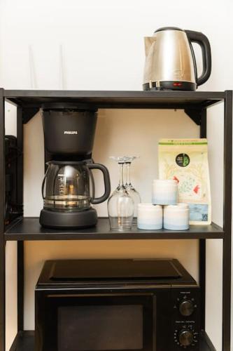 a shelf with a coffee maker on top of a microwave at Airport Runway View from terrace|Coffee Maker|Luxe in Pune