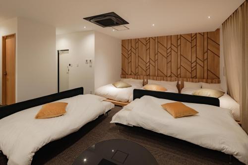a bedroom with two beds and a table in it at LUX by Hotel BAL in Fukuoka