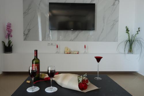a table with two glasses of wine and a television at Kallithea View in Prasás
