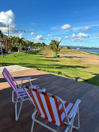 two chairs sitting on a deck near the beach at Apartamento Beira Rio no Condomínio Brisas do Lago in Paulo Afonso