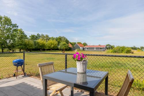 a table with a vase of flowers on a fence at Welcome in - Vakantiewoning Jikkemien met terras, vrij uitzicht en huisdiervriendelijk in Koudekerke
