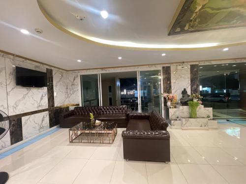 a living room with leather couches and a tv at Carpediem Hotel in Rayong