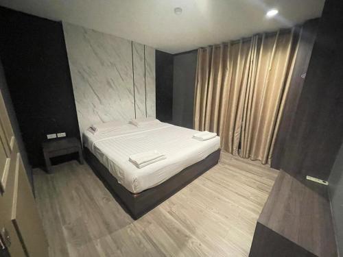 a small bedroom with a bed with white sheets at Carpediem Hotel in Rayong