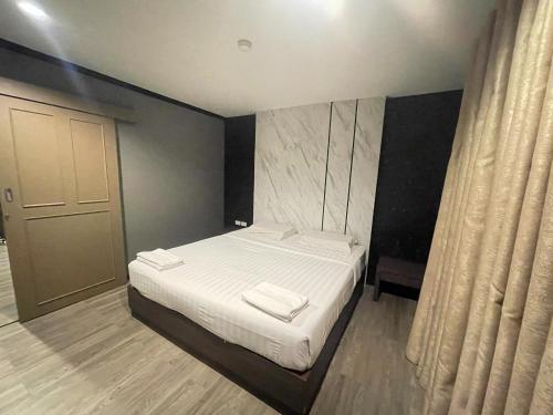 a bedroom with a bed with two towels on it at Carpediem Hotel in Rayong