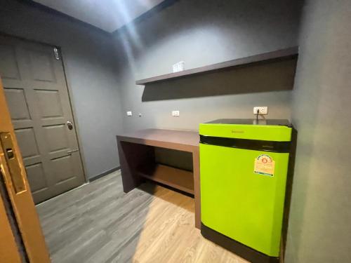 a green refrigerator in a room with a desk at Carpediem Hotel in Rayong