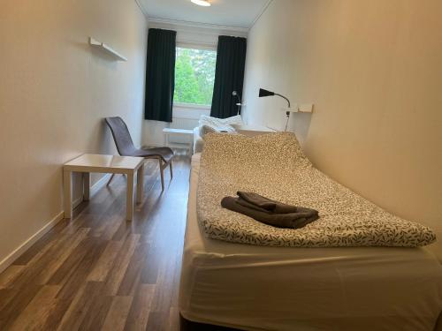 a bedroom with a bed with a desk and a chair at Rentalux Hostel - Budget Double & Single rooms in Timrå