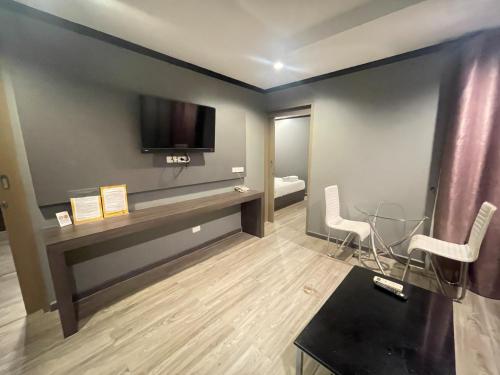 a room with a tv and a table and chairs at Carpediem Hotel in Rayong