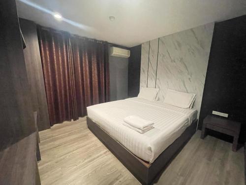 a small bedroom with a bed with white sheets at Carpediem Hotel in Rayong