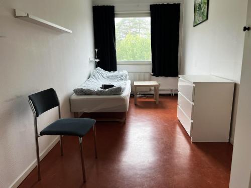 a bedroom with a bed and a chair and a window at Rentalux Hostel - Budget Double & Single rooms in Timrå