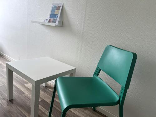 a green chair sitting next to a white table at Rentalux Hostel - Budget Double & Single rooms in Timrå