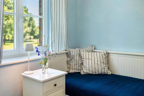 a bedroom with a blue bed with pillows and a table at Der Flusshof, Ferienhaus in Werben