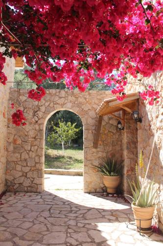 a stone archway with red flowers on a wall at Dioni Villa in Sivota