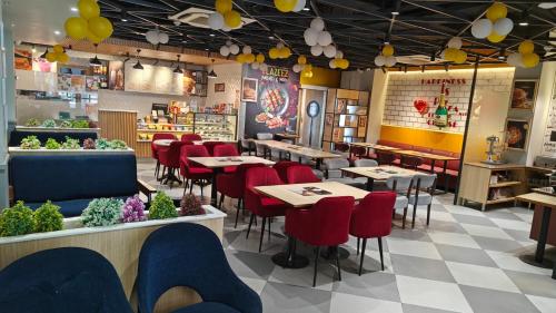 a restaurant with tables and red chairs in a room at Hotel Luxurio - In-House Barista Cafe, Near Golden Temple Amritsar in Amritsar