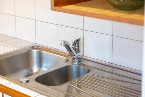 a stainless steel sink in a kitchen with white tiles at Gite Cheminée, Kerantum, Au Calme in Mahalon