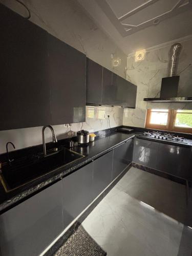 a kitchen with black cabinets and a sink at Tranquil trails home stay naddi in Dharamshala