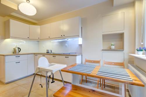 cocina con armarios blancos, mesa y sillas en Apartament Brzeźno, en Gdansk