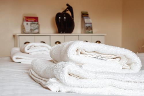 a pile of white towels sitting on top of a bed at Spacious Holiday Home with Free Parking in Harrogate