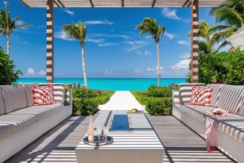 a patio with a view of the ocean and palm trees at Villa Azure Turks Caicos in Leeward