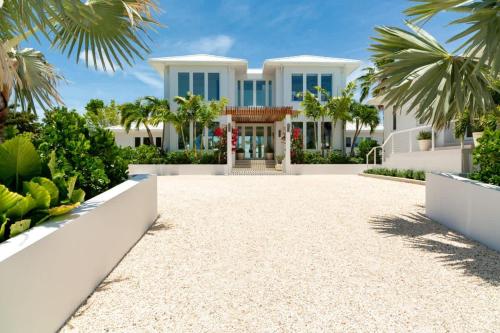 a white house with palm trees and a driveway at Villa Turquoise Turks Caicos in Leeward