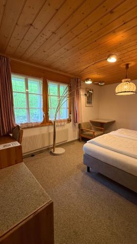 a bedroom with a bed and a table and windows at Hotel Châlet Du Lac in Iseltwald