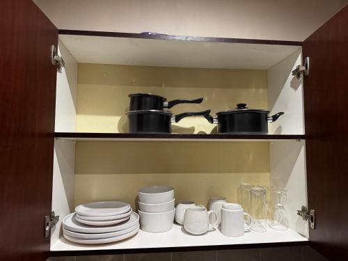 a cupboard with cups and plates and pots and pans at The olive stay at Edwardian unit F7 in Port Edward