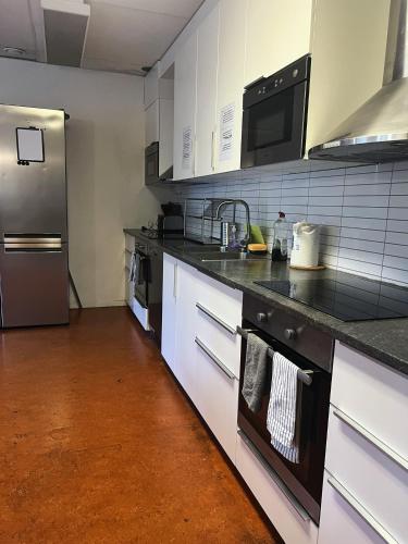 a kitchen with white cabinets and a stainless steel refrigerator at Rentalux Hostel - Budget Double & Single rooms in Timrå