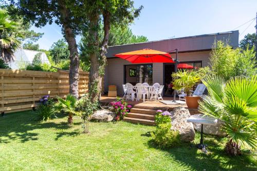 a backyard with a patio with a red umbrella at Villa Léonie in Trégunc
