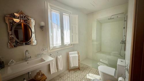 a bathroom with a sink and a toilet and a mirror at Casa Pizarro Hotel in Cáceres