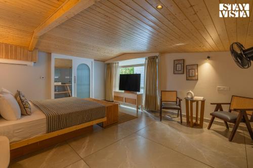 a bedroom with a bed and a television in it at StayVista at The Ever House with Bonfire, Jacuzzi, Bathtub in Dharampur