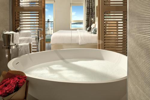 a white bath tub in a bathroom with a bedroom at The Chedi Luštica Bay in Tivat