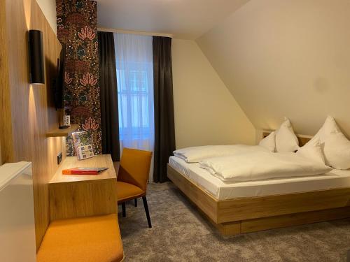 a bedroom with a bed and a desk and a bed and a window at Akzent Hotel Schranne in Rothenburg ob der Tauber