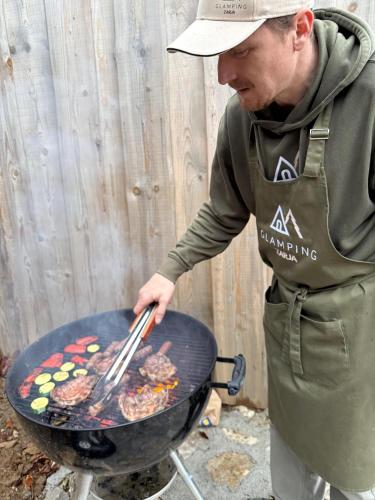 a man is cooking food on a grill at Glamping Zarja, Vipava Valley in Zoll