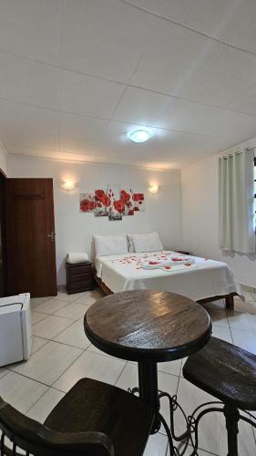 a bedroom with a bed and a table and chairs at Pousada Recanto da Mata in Marechal Floriano