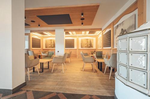 a waiting room with tables and chairs and a flat screen tv at Aparthotel Des Alpes in Cavalese