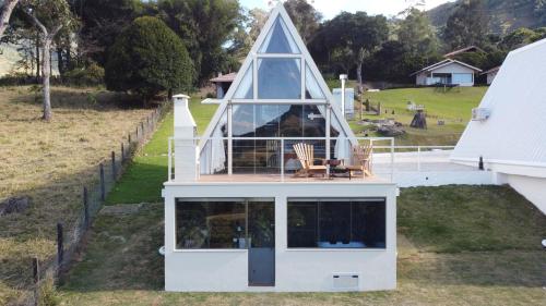 a house with a triangular roof on top of it at Chalés Quinta da Boa Vista in São Bento do Sapucaí