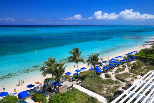 een luchtzicht op een strand met blauwe parasols en de oceaan bij Windsong on the Reef in Grace Bay